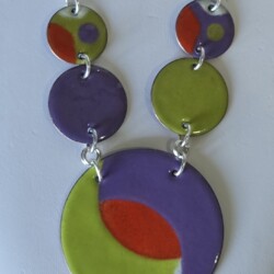 Gorgeous abstract design in peridot green, orange, and purple enamel on copper disks. Sterling silver and metallic black chain. $165 SOLD